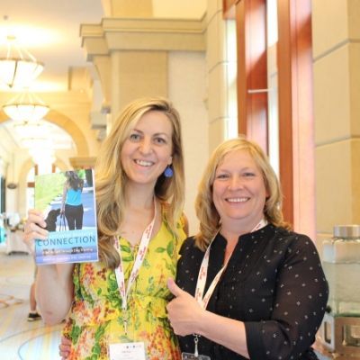 Marissa Martino poses with another woman, holding her dog training and behavior book