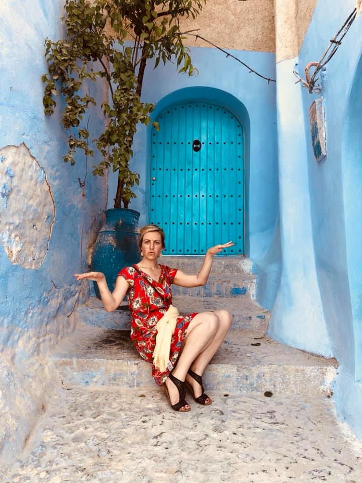 Marissa Martino, a dog behavior consultant, sits on steps in front of a blue door