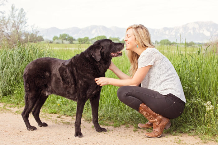 Marissa Martino crouches in front of a black dog, showing how to use  nonviolent communication with dogs