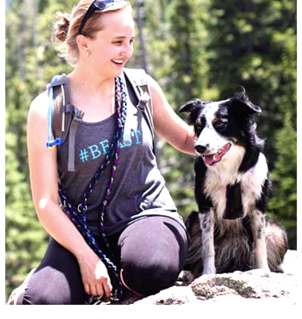 Sarah Stremming, a founder of an online dog training course, sits on a rock with a black and white dog