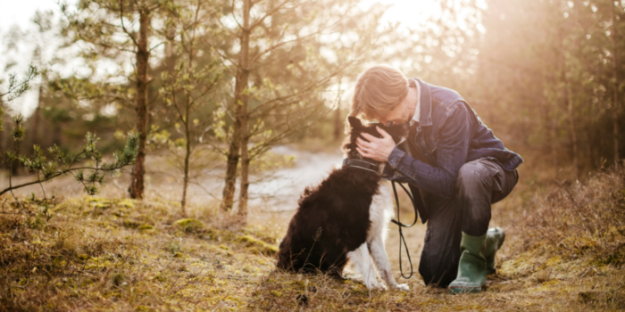 A woman bends down and hugs her dog while learning how to manage difficult emotions